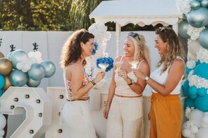Three individuals at an outdoor event with balloons and a white structure. - The Reef 7C - Island Horizon (Noord)