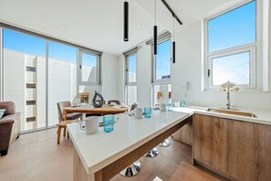 Eine moderne Küche mit einer großen Kochinsel, viel Tageslicht und Blick durch die Fenster.