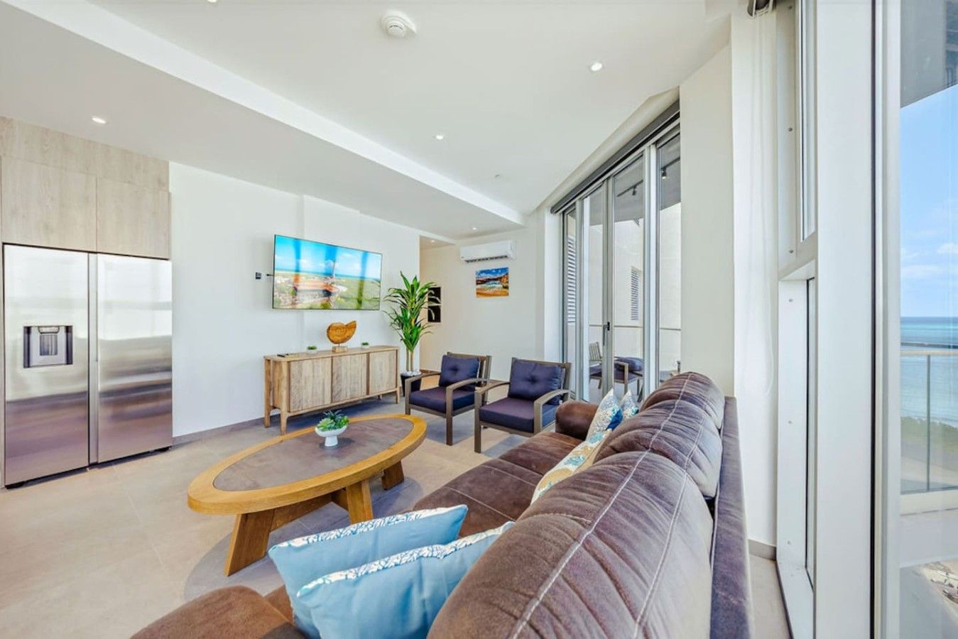 Un salon moderne avec un grand canapé, une table basse et un téléviseur fixé au mur.