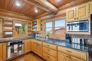 Eine Landhausküche mit Holzschränken, einem Edelstahlbackofen, einer Mikrowelle und einer Kaffeemaschine.
