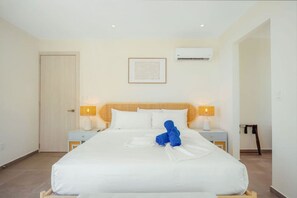 Quarto de hotel com cama, duas mesas de cabeceira, ar condicionado fixado na parede e um quadro emoldurado.