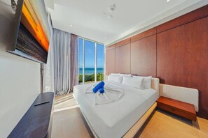 A modern hotel room with a large bed, a flat-screen TV, and a view of the ocean. - The Reef 4A - Blue Horizon (Noord)