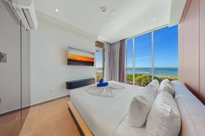 A modern hotel room with a large bed, a flat-screen TV, and a view of the ocean. - The Reef 4A - Blue Horizon (Noord)