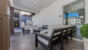 A spacious outdoor seating area with a modern design, featuring a large table and multiple sofas.