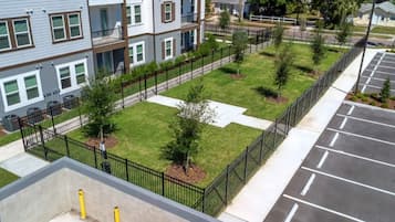 A multi-story residential building with a fenced courtyard, a parking area, and a visible cross-shaped pavement.