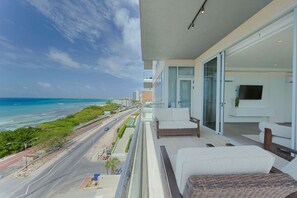 A balcony with a view of the ocean, a sofa, and a TV. - The Reef 6A - Ocean Pearl (Noord)