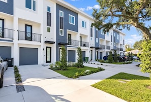 A modern multi-story residential building with a clean, contemporary design, featuring balconies and a well-maintained front yard. - Modern Downtown Tampa Townhome | Near Riverwalk (Tampa)