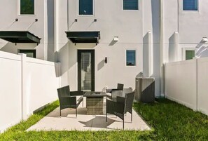 A patio with a table and chairs, a small grill, and a white fence. - Modern Downtown Tampa Townhome | Near Riverwalk (Tampa)