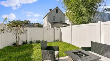 A backyard with a fire pit, two chairs, and a white fence.