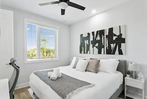 A modern bedroom with a bed, a ceiling fan, a window with blinds, and a wall-mounted artwork. - Modern Downtown Tampa Townhome | Near Riverwalk (Tampa)