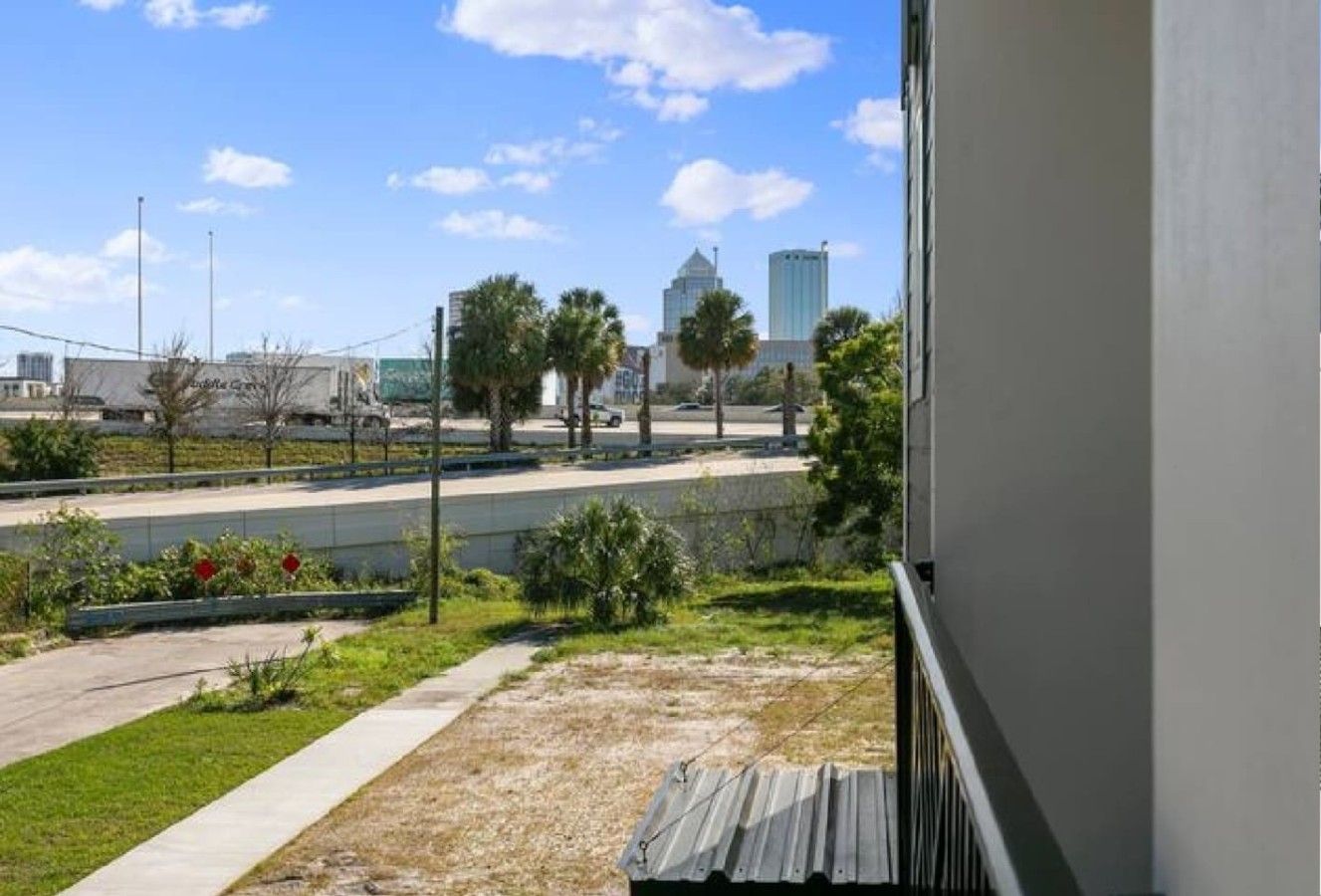 A view from a balcony overlooking a parking lot with a building in the background.