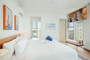 Ein modernes Hotelzimmer mit einem großen Bett, einer Sitzecke mit Blick und Kunstwerken an den Wänden.