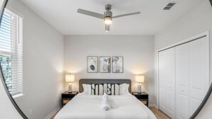 Una camera da letto con un letto, due comodini con lampade, una ventola a soffitto e un armadio.