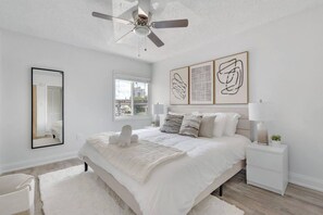 A bedroom with a bed, bedside tables, a ceiling fan, a window, and artwork on the wall. - Bayside Tampa Escape | Pool, Gym & Parking (Tampa)