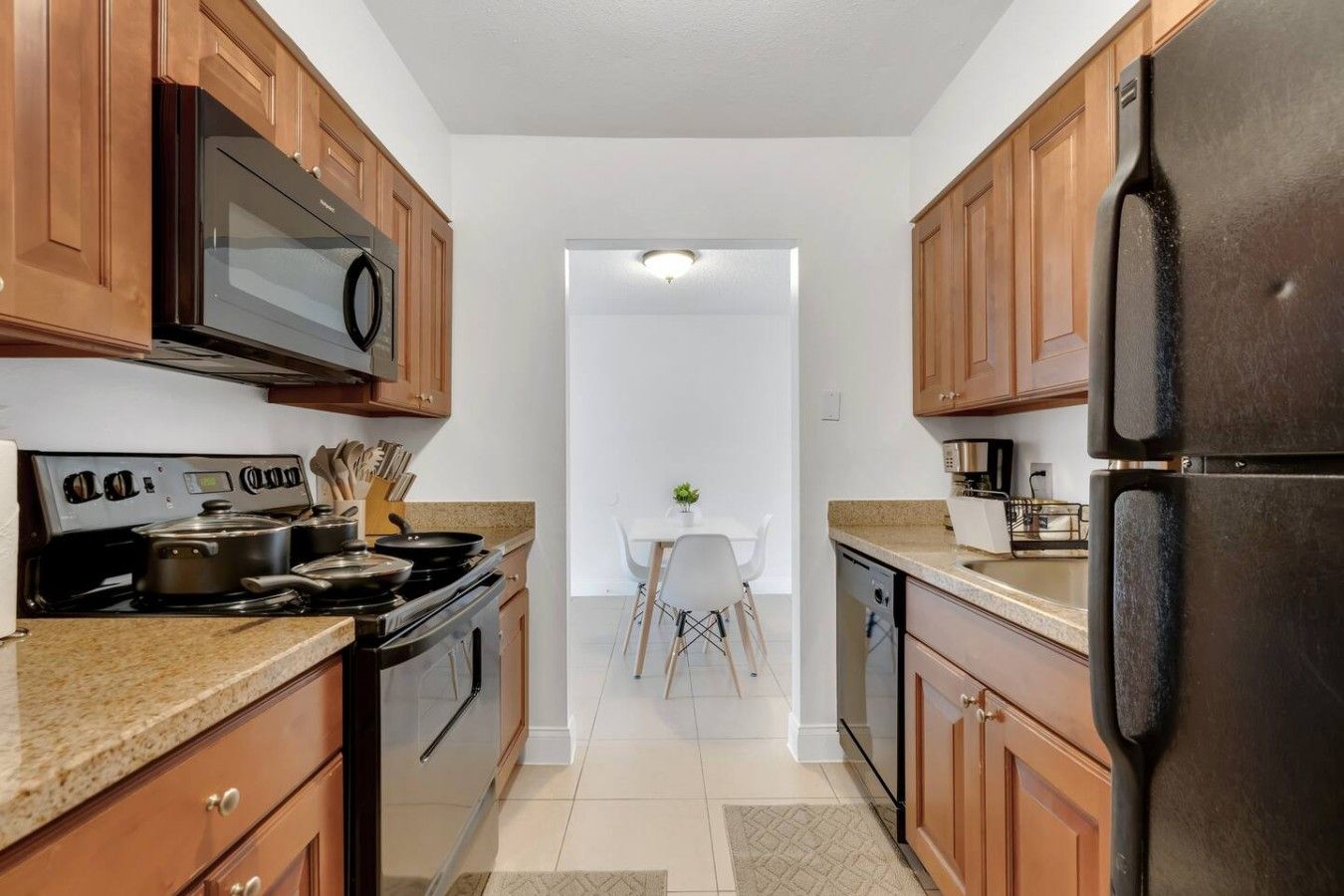 Una cocina con gabinetes de madera, estufa, microondas y refrigerador.