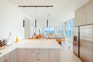Een moderne keuken met een centraal eiland, grote ramen en uitzicht op de oceaan.