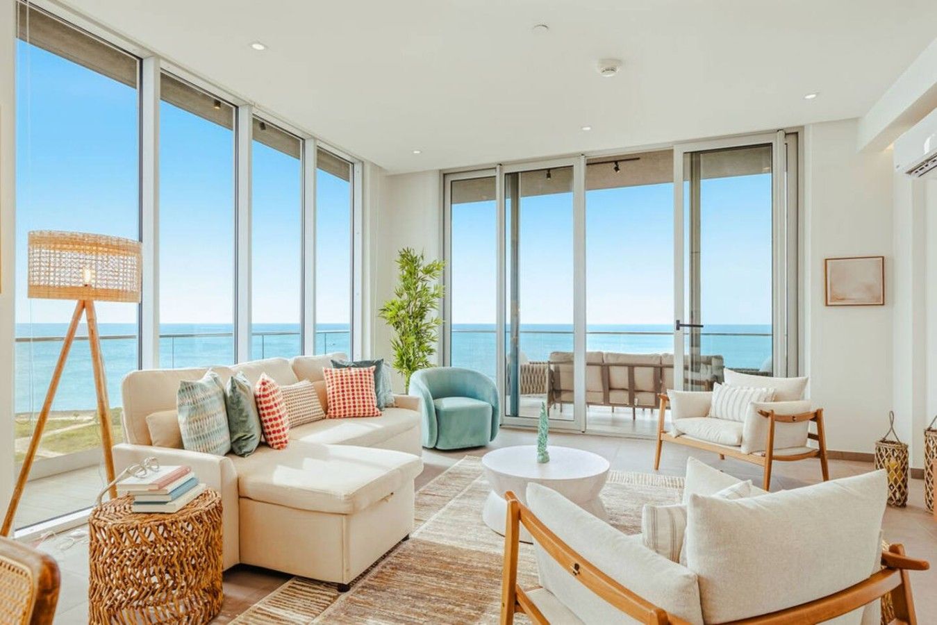 Un amplio salón con un gran ventanal con vistas al mar, amueblado con un sofá, sillones y una mesita de centro.