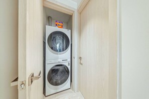 Une buanderie avec deux machines à laver superposées et une boîte de lessive Tide posée sur le dessus.