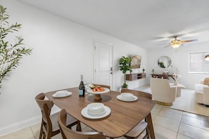 Een eetgedeelte met een houten tafel, stoelen en een plafondventilator.