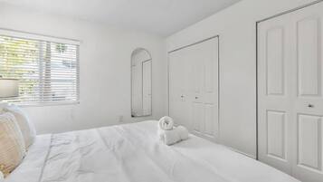 Une chambre à coucher comprenant un lit, une table de chevet, une lampe, un miroir et une armoire.