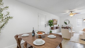 A dining area with a wooden table, chairs, and a white door in the background. - Bayshore Retreat | Pool, Gym & Free Parking (Tampa)