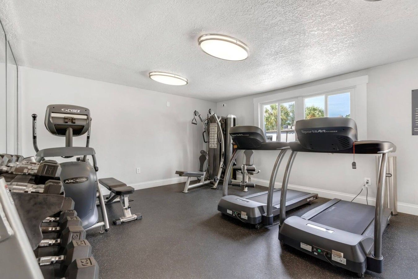 A home gym with treadmills, a stationary bike, and free weights.