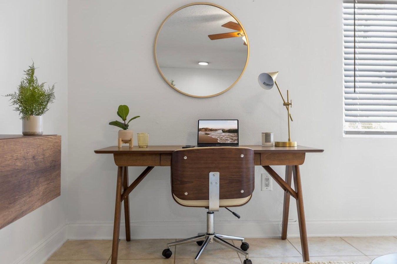 Een houten bureau met een computer, een spiegel en een lamp. Er staat een stoel voor het bureau.