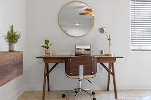 A wooden desk with a computer, a mirror, and a lamp. There is a chair in front of the desk. - Bayshore Retreat | Pool, Gym & Free Parking (Tampa)