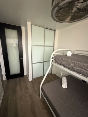 A bedroom with a bunk bed, a ceiling fan, a door with frosted glass panels, and a wooden floor. - 3-Bed. Modern loft with gated parking near SJU (San Juan)