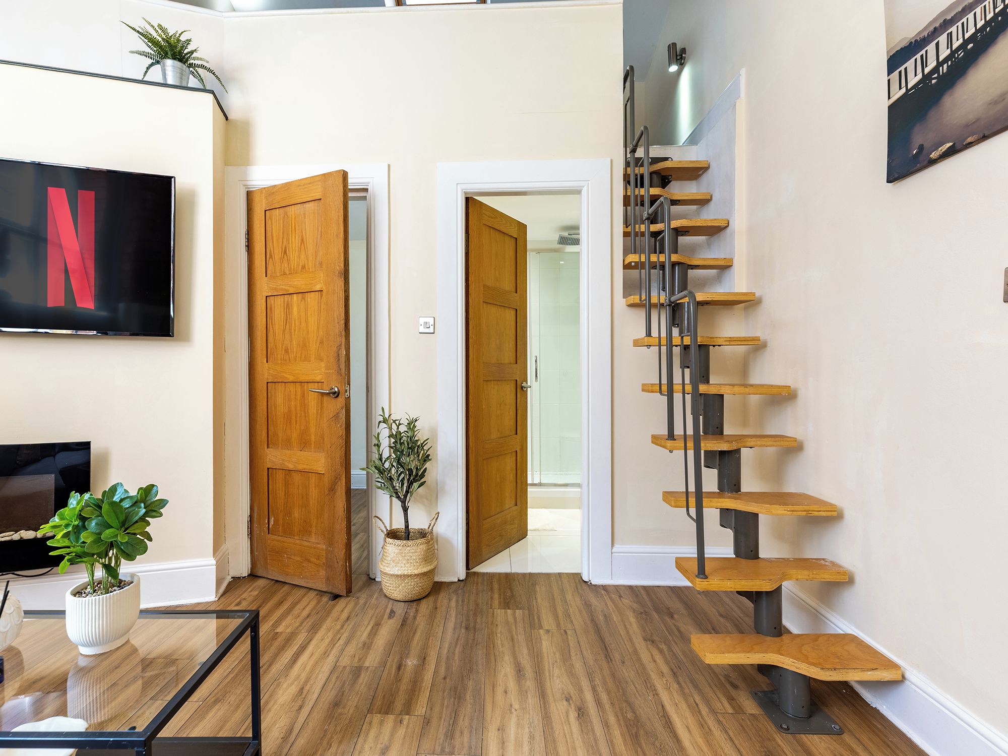 A modern interior with a wooden staircase, a television, and a plant.