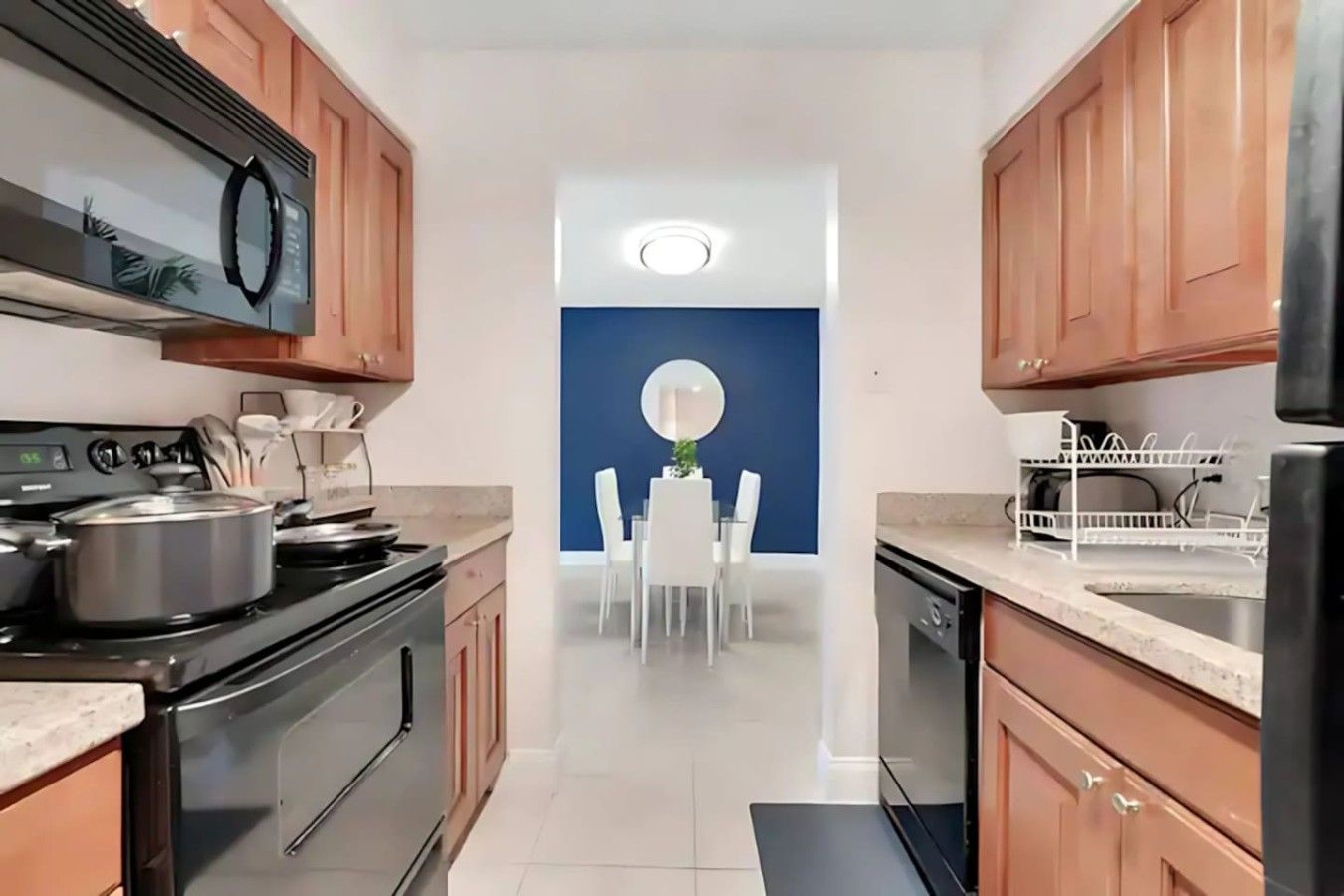 A modern kitchen with wooden cabinets, a stove, and a dining area with a blue accent wall.