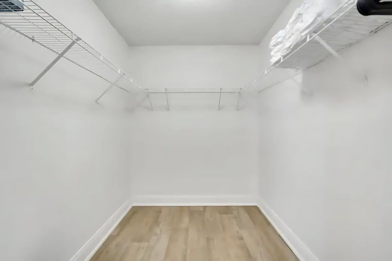 A small, empty room with white walls and a wooden floor.