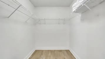 Um quarto pequeno e vazio, com paredes brancas e chão de madeira.