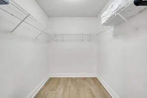 Een kleine, lege kamer met witte wanden en een houten vloer.
