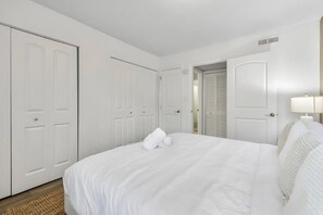Ein Hotelzimmer mit einem großen Bett, weißen Vorhängen, einer Nachttischlampe und einer Tür zu einem Schrank.