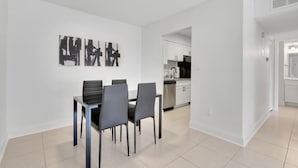 Un comedor moderno con una mesa y sillas, una cocina al fondo y un pasillo que conduce a otra habitación.