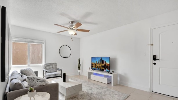 Una sala de estar moderna con sofá, mesa de centro, televisor y ventilador de techo.