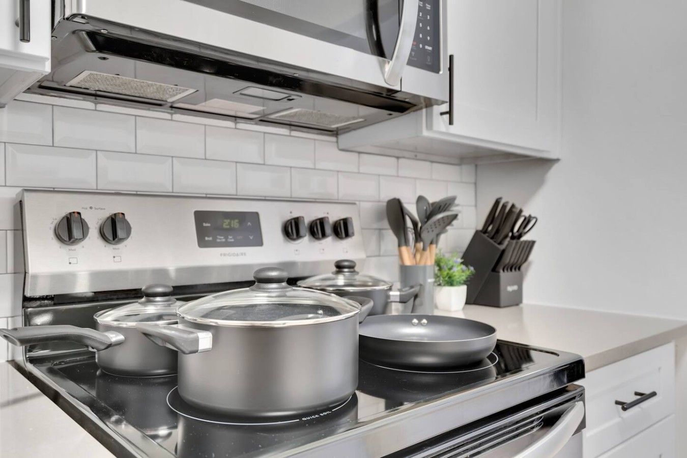 A modern kitchen with a stainless steel stove, pots, and a digital control panel.