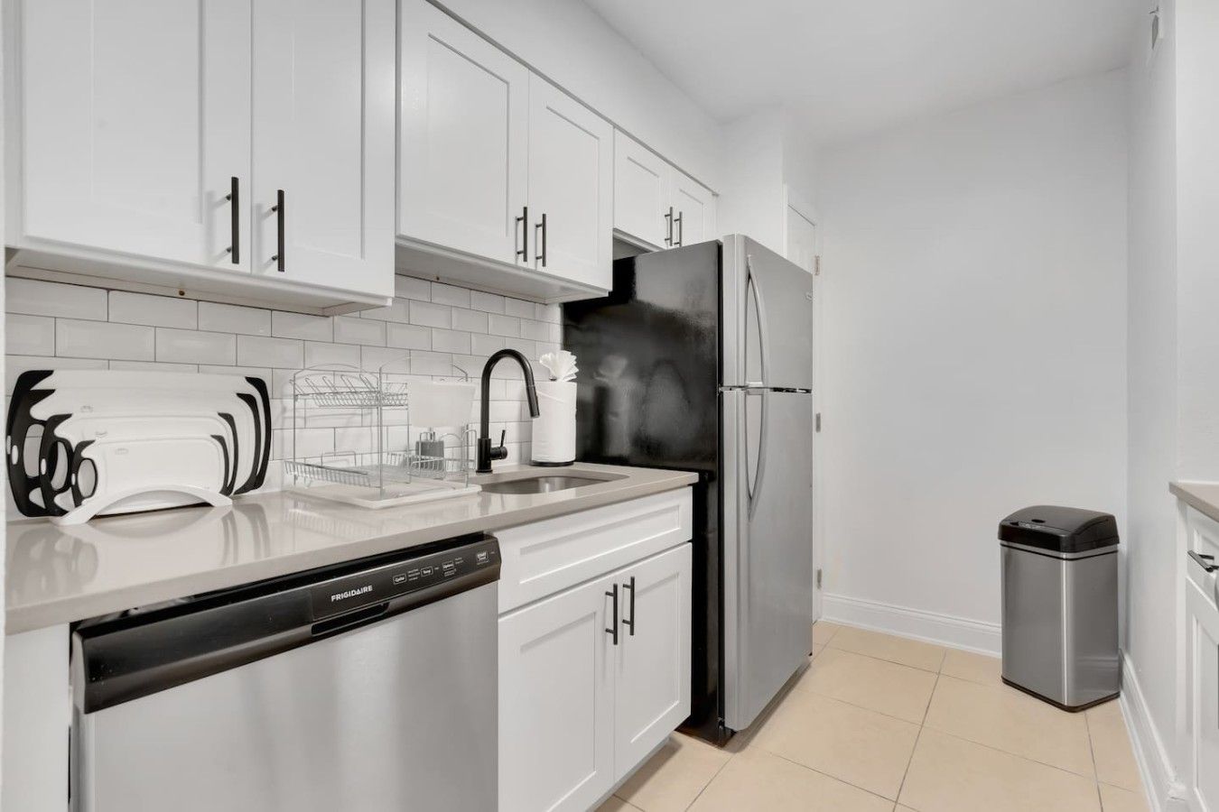Una cocina moderna con electrodomésticos de acero inoxidable, armarios blancos y lavavajillas.