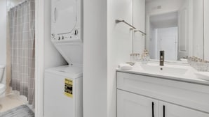 Un baño moderno con lavamanos blanco, espejo y cortina de ducha.