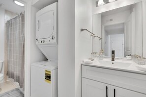 Een moderne badkamer met een wit wastafelmeubel, spiegel en douchegordijn.