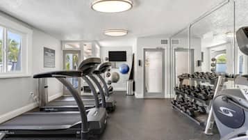 A fitness center with treadmills, a wall-mounted exercise ball, and a rack of dumbbells.