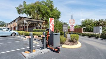 A parking area with a sign for a leasing center, a tow-away zone sign, and a building with a covered entrance.
