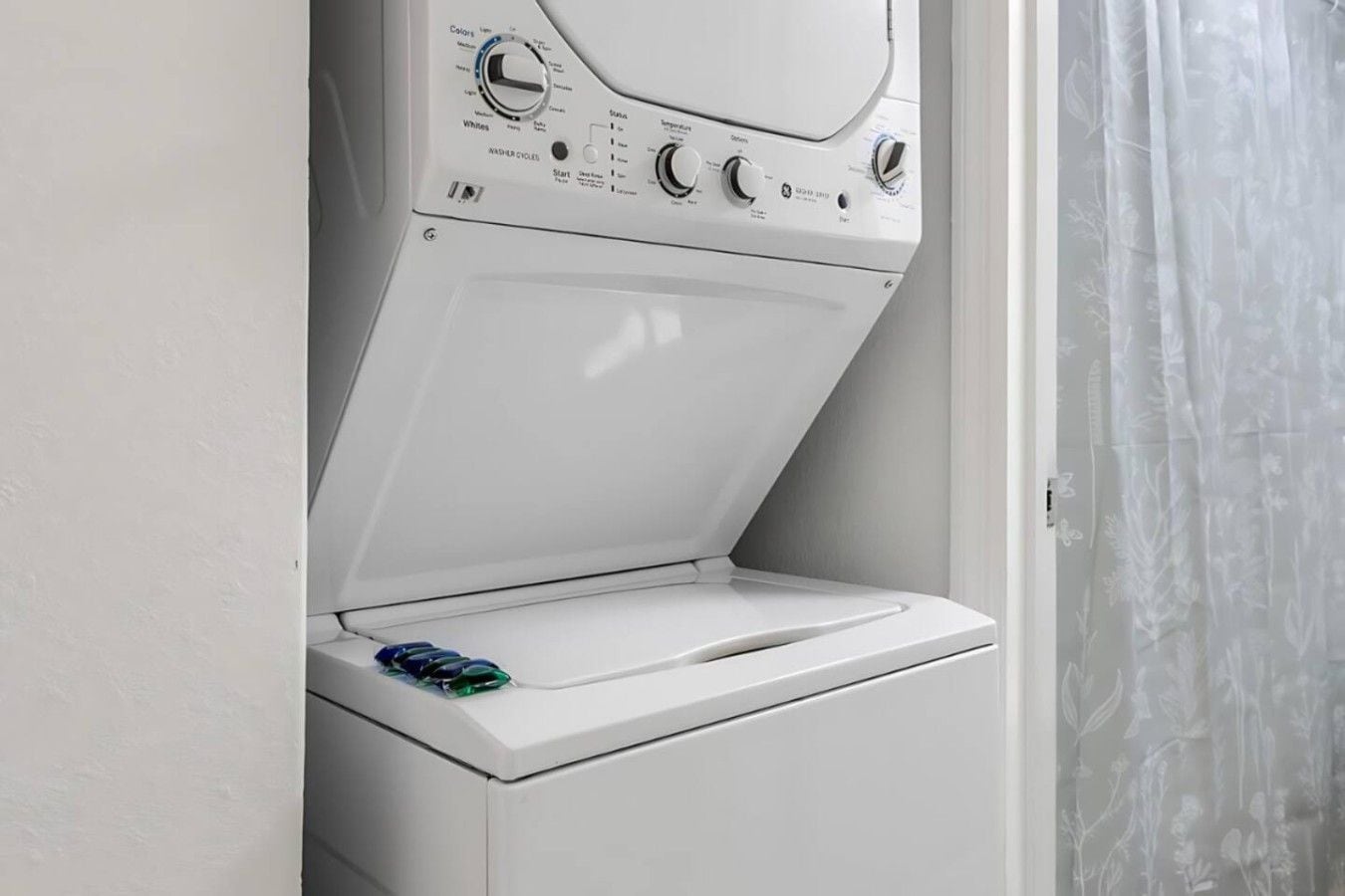 A front-loading washing machine with a control panel, a door, and a curtain.