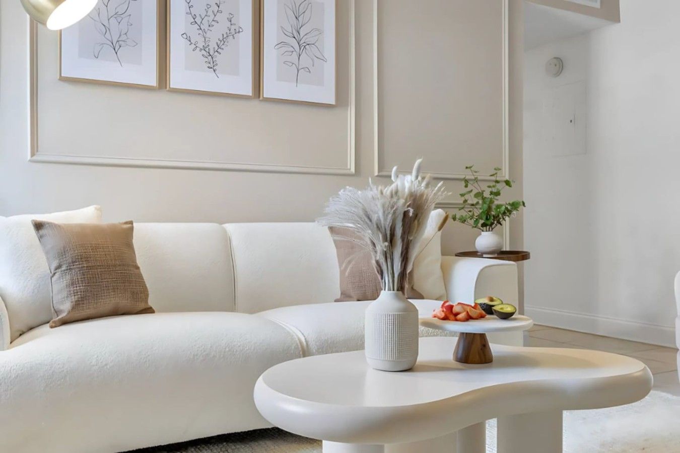Una sala moderna con un sofá blanco, una mesita pequeña y un estante montado en la pared con una planta.
