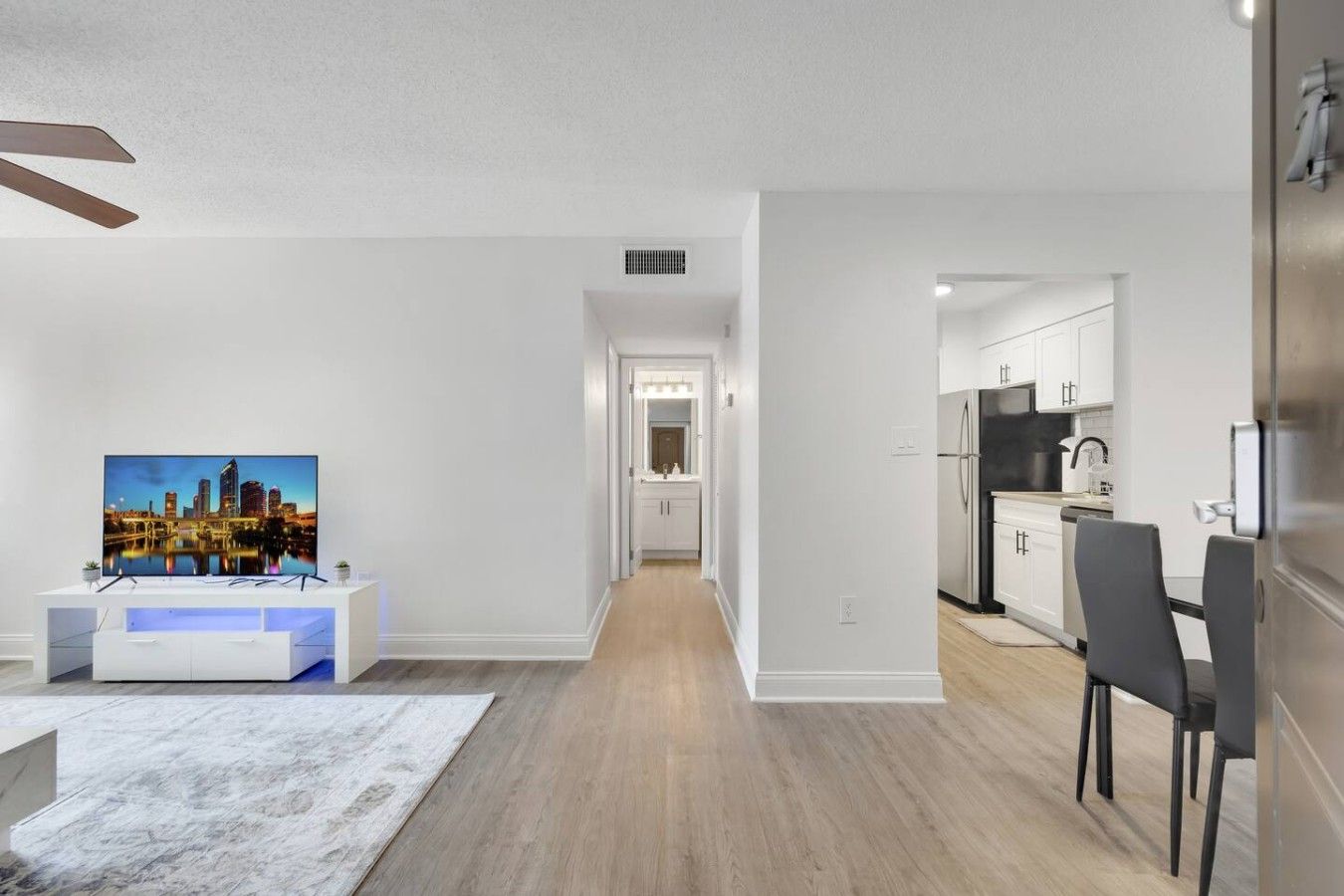 Un apartamento moderno con sala de estar, cocina y un pasillo que lleva a un baño.