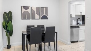 A dining area with a table and chairs, a potted plant, and three abstract wall art pieces. - South Tampa Coastal Stay | Pool & Free Parking (Tampa)