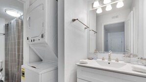 A modern bathroom with a white vanity, a large mirror, and a shower area. - South Tampa Coastal Stay | Pool & Free Parking (Tampa)