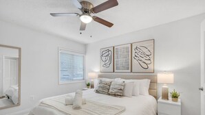A bedroom with a bed, bedside lamps, a ceiling fan, and artwork on the wall. - Bayshore Bliss | Pool, Gym & Free Parking (Tampa)