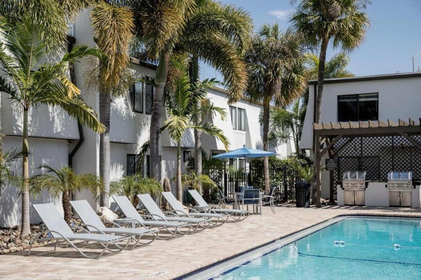 A poolside area with lounge chairs and a barbecue setup.